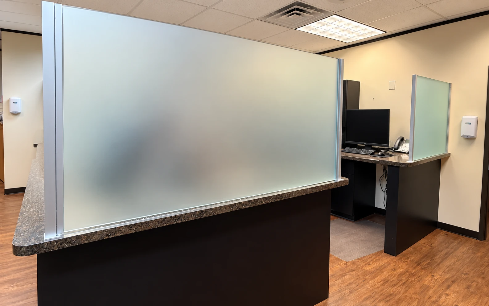 Frosted privacy partition with aluminum framing above a commercial reception counter.